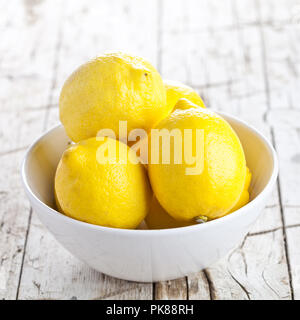 Frische Zitronen in einer Schale auf der rustikalen Holzmöbeln Hintergrund Stockfoto