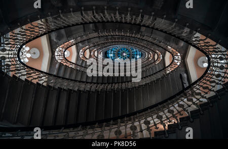 Blickfang Bild mit Treppe Design in eine Spirale bilden, ein Muster der ovale Figuren, von Kronleuchtern beleuchtet, betrachtet aus unter, in Genua, Italien. Stockfoto