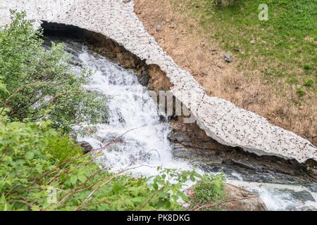 Bleibt der Eis- und Schneedecke über einem Bergbach im Sommer, Österreich Stockfoto