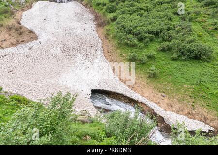 Bleibt der Eis- und Schneedecke über einem Bergbach im Sommer, Österreich Stockfoto