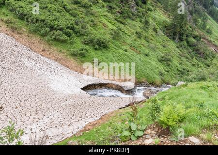 Bleibt der Eis- und Schneedecke über einem Bergbach im Sommer, Österreich Stockfoto
