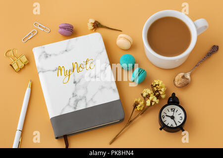 Frau Arbeitsbereich mit Blumen, Makronen, Notebooks, Pen, Kaffee Tasse und vintage Löffel Stockfoto