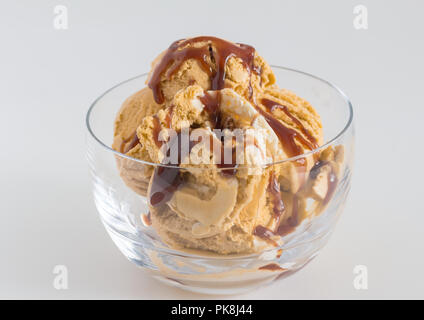 Eis in Glasschale - Caramel und Vanille Eis beträufelt mit Schokolade Sirup hautnah. Stockfoto