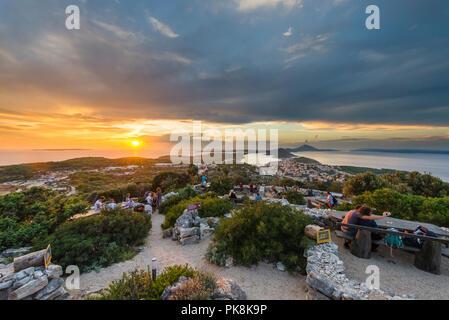 Die Leute sitzen auf den Bänken der Providenca Bar und die Aussicht auf den Sonnenuntergang über der Insel Lošinj und Cres, Kvarner Bucht, Kroatien genießen Stockfoto