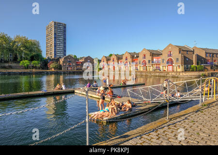 Shadwell Becken, London, UK - 7. Mai 2018: Junge Menschen in der Sonne und Sonnenbaden auf dem Kai Seite und ponton der Shadwell Becken. Stockfoto