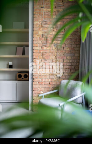 Trendy Büro im Loft Stil mit grauem und Mauerwerk. Es ist eine hölzerne Regale mit einem Lautsprecher und Frames, Schließfächer, grau Sessel, Vorhang, g Stockfoto