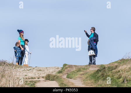 Ein Vater, der ein Foto von einer Mutter und ihren Töchtern während eines Aufenthalts in Towan Head in Newquay Cornwall gemacht hat. Stockfoto