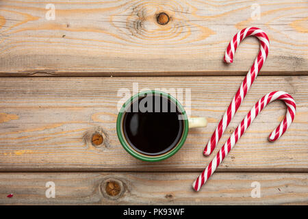 Der Weihnachtszeit. Zuckerstangen und eine Tasse Kaffee auf Holz- Hintergrund, Kopieren, Ansicht von oben Stockfoto