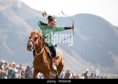 Stadt Cholpon-Ata, Kirgisistan - Sep 6, 2018: Weibliche Bogenschützen auf ein Ziel während einer traditionellen reiten Bogenschießen Wettbewerb zum Ziel haben. Stockfoto