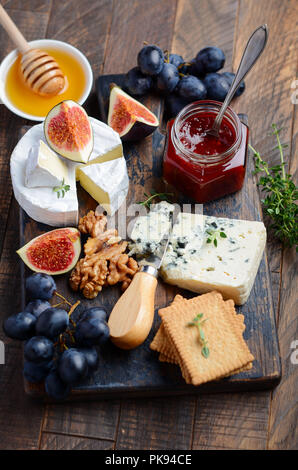 Käseplatte mit Trauben, Feigen, Cracker, Honig, Pflaumen Gelee, Thymian und Muttern, selektive konzentrieren. Stockfoto