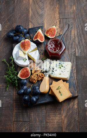 Käseplatte mit Trauben, Feigen, Cracker, Honig, Pflaumen Gelee, Thymian und Muttern, selektive konzentrieren. Stockfoto