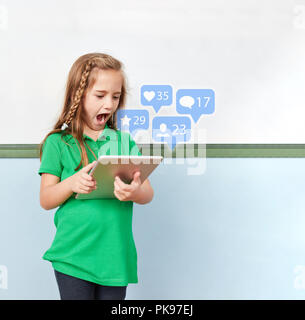 Mädchen ist bei vielen mag und Kommentare auf Tablet Computer in der Schule begeistert Stockfoto