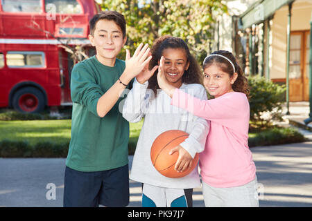 Multikulturellen Studenten mit Basketball motivieren sich mit einem hohen fünf Stockfoto