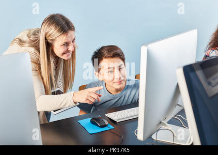 Lehrerin hilft ein Schüler mit dem Computer in der Schule zu erlernen Stockfoto