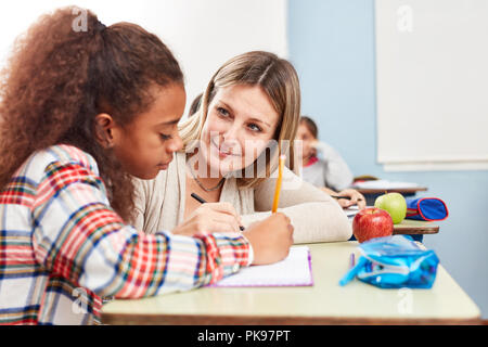 Frau als Lehrerin gibt Nachhilfe Schülerin im Klassenzimmer einer Grundschule Stockfoto