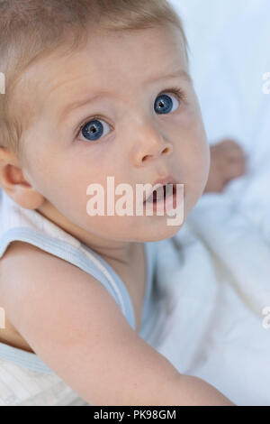 Nachdenklich ruhigen adorable kleine blaue Augen baby boy an der Kamera in ein Kinderbett in der Nähe zu 7/8 Portrait starrte Stockfoto