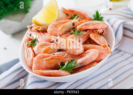Gekochte Garnelen oder Krabben auf einer weißen Schüssel auf einem weißen Tisch. Fisch und Meeresfrüchte. Stockfoto