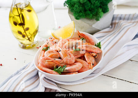 Gekochte Garnelen oder Krabben auf einer weißen Schüssel auf einem weißen Tisch. Fisch und Meeresfrüchte. Stockfoto