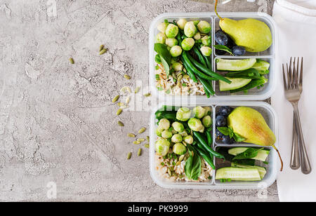 Vegane grüne Mahlzeit prep Container mit Reis, Bohnen, Rosenkohl, Gurke und Obst. Abendessen in Lunch Box. Ansicht von oben. Flach Stockfoto