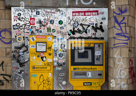 Eingefügt und verschmiert Letter Box und Stempel Automat in einem Postamt im Stadtteil Ehrenfeld, Köln, Deutschland beklebter Briefkasten und beschmierter Stockfoto