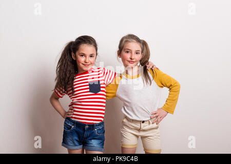 Kleine Mädchen in einem Studio stehend, die Arme um einander. Stockfoto