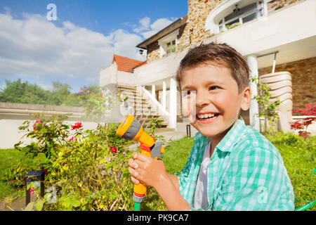 Cute boy Bewässerung Garten mit hand Sprinkler Stockfoto