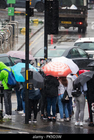 UK Wetter. Menschen unter Regenschirmen in ein heftiger Regenschauer, während sie darauf warteten, die Straße zu überqueren, in Liverpool, Großbritannien gefangen. Stockfoto