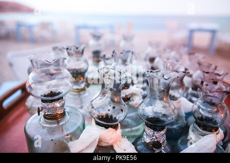 Altes Öl Glas Lampen mit DIY-Fixes auf Tisch versammelte sich am griechischen Strand bei Sonnenuntergang Stockfoto