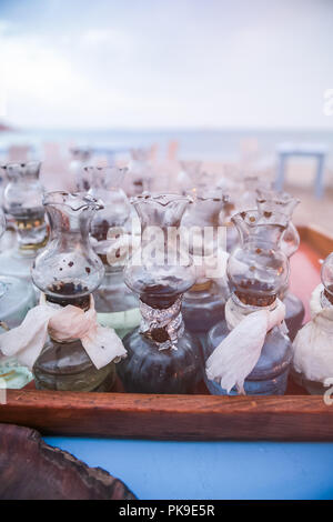 Altes Öl Glas Lampen mit DIY-Fixes auf Tisch versammelte sich am griechischen Strand bei Sonnenuntergang Stockfoto