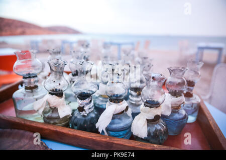 Altes Öl Glas Lampen mit DIY-Fixes auf Tisch versammelte sich am griechischen Strand bei Sonnenuntergang Stockfoto