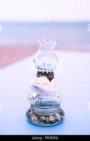 Altes Öl Glas Lampen mit einer Papierserviette auf blauen Tabelle am griechischen Strand bei Sonnenuntergang Stockfoto