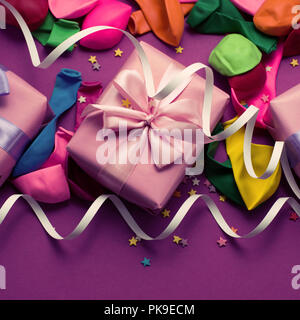 Festliche Hintergrund violett Material bunte Luftballons luftschlangen Konfetti drei Boxen Geschenk. Ansicht von oben flach kopieren Raum toning Stockfoto
