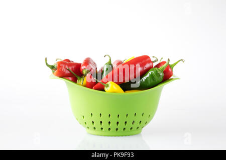 Capsicum annuum. Chilis in einer grünen Sieb. Stockfoto