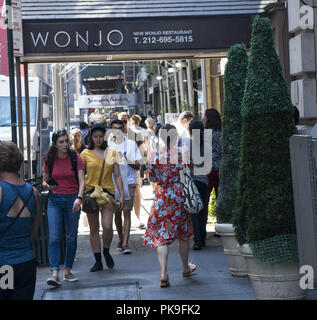 Menschen gehen, Essen und Einkaufen in Korea Town auf der 32nd St. zwischen 5. und 6. Avenue in Manhattan, New York City. Stockfoto