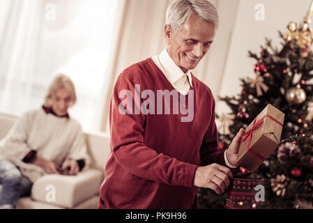 Interessierte angenehmer Mensch und lächelnd ein Geschenk. Stockfoto