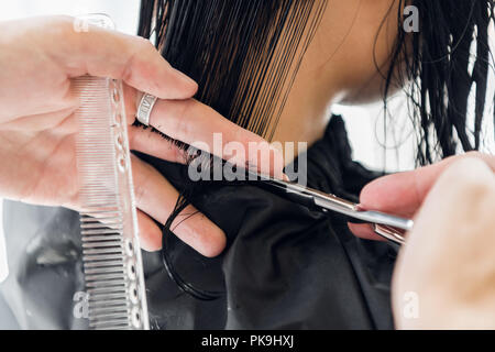 Man Hände und Kamm weiblich dunkel braune Haare in einem Schönheitssalon mit Spiegel Stockfoto