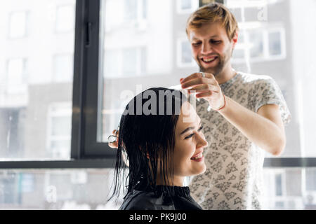 Lachende Mädchen und Friseur sprechen und lächelnd, während Sie einen neuen Haarschnitt oder Frisur Stockfoto