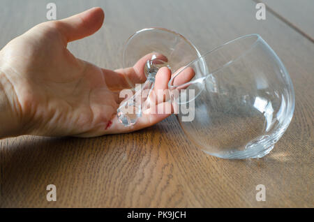 Woman's Hand mit Blut halten gebrochen Wein Glas auf Holz- Hintergrund. Stockfoto