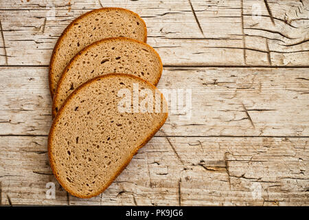 Drei Scheiben Roggenbrot mit rustikalen Holzmöbeln Hintergrund Stockfoto