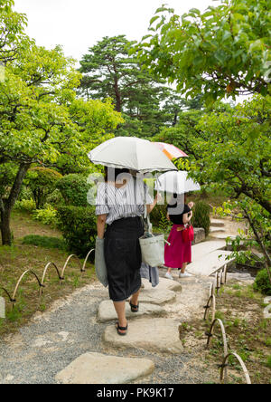 Japanische Frauen gehen mit Sonnenschirme in Kenroku-en Garten, Präfektur Ishikawa, Kanazawa, Japan Stockfoto
