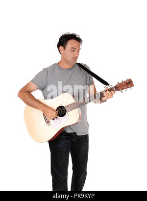 Ein junger stattlicher Mann mit seiner Gitarre und Wiedergabe eines Songs in Jeans und T-Shirt, auf weißem Hintergrund Stockfoto