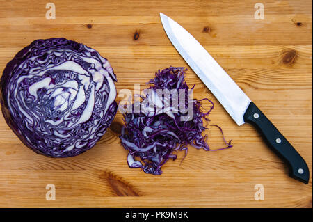 Schneiden Sie Rotkohl und Messer auf Schneidebrett. Kulinarische noch leben. Stockfoto