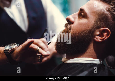 Barbershop mit Interieur aus Holz. Bärtige Modell Mann und Friseur. Stockfoto