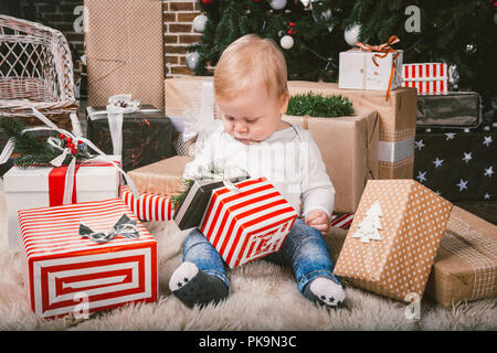 Thema Winter und Weihnachten. Kind Junge kaukasier blond 1 Jahr alt Sitzen home Stock in der Nähe Weihnachtsbaum mit neuen Jahr Dekor auf shaggy Teppich Stockfoto