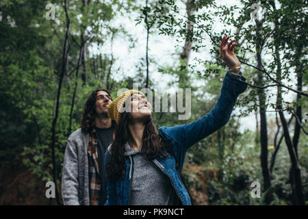Schöne Frau mit ihrem Freund zu Fuß durch den Wald. Paar gute Zeit im Regenwald. Zu den Bäumen und lächelnd. Stockfoto