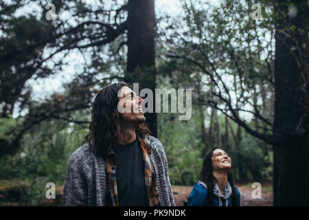 Junger Mann im Wald mit ihrer Freundin auf der Rückseite und die Aussicht genießen. Man bewundert die Natur mit Frau zurück in den Wald. Stockfoto