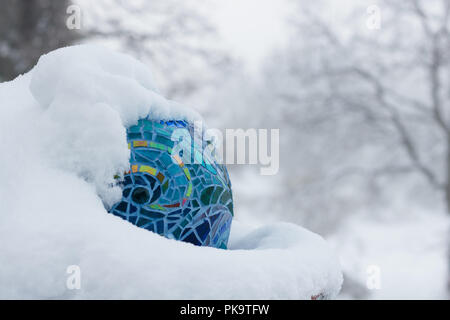 Kalten Schnee Tag mit close-up mit Schattierungen von Blau, Aqua, Grün, Gold, hellen bunten Glasmalereien Mosaik garten Kunst in Winter kuschelte sich umarmen Stockfoto