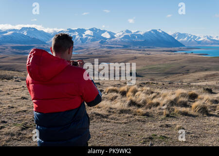 Mann mit Action Kamera ein Foto von Bergen und See in Neuseeland Stockfoto