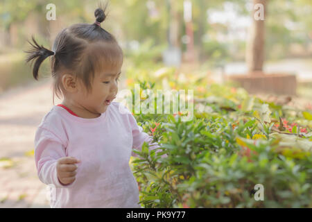 Baby Mädchen zu Fuß in den öffentlichen Park mit Mutter, sie war entschlossen, die Blumen, die Sie zum ersten Mal in ihrem Leben begegnet war, zu sehen. Stockfoto