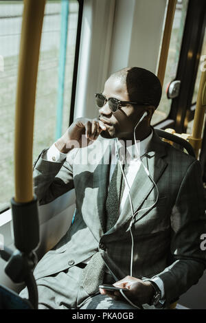 Afrikanische amerikanische Geschäftsmann tragen Anzug das Hören von Musik während der Zug Stockfoto